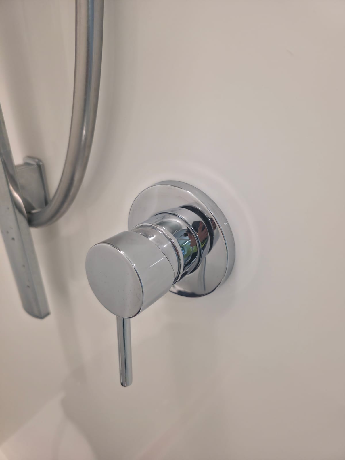 Detail of a polished chrome shower mixer and wall plate